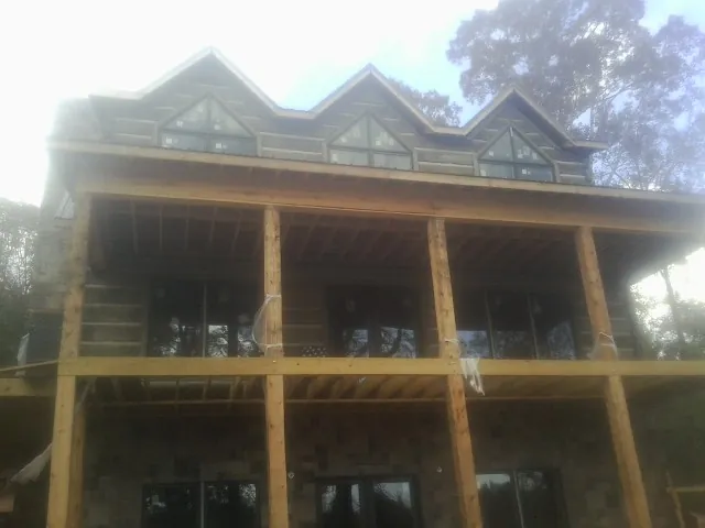 Dormers and porch framing on a large log home under construction — Roof Coating work by our crew in Grand Rapids